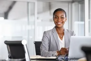 About GEMS - black lady sitting at computer-300x200px